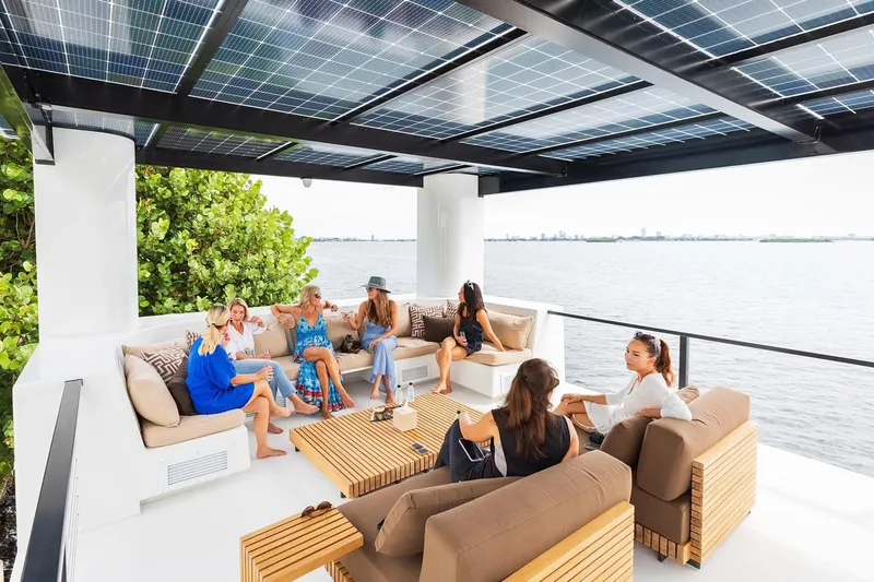  Yacht Photos Pics Group relaxing on Arkup 50 yacht's deck with solar panels, overlooking water.