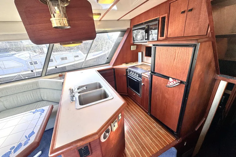  Yacht Photos Pics 1989 Bayliner 4588 Pilothouse interior with kitchen, sink, stove, and seating area.