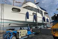 2016 Beneteau Swift Trawler 44 on dry dock with blue fenders, under a cloudy sky.