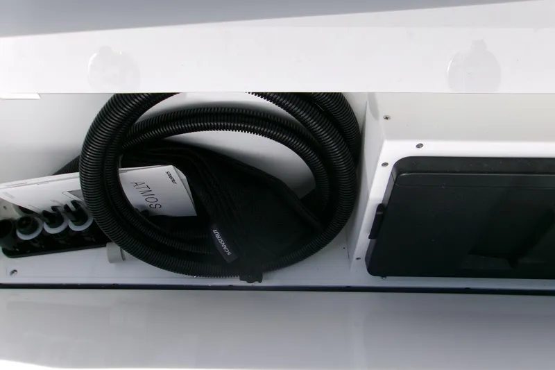  Yacht Photos Pics Storage compartment in 2026 Sportsman Heritage 321 Center Console boat, featuring coiled hose and manuals.