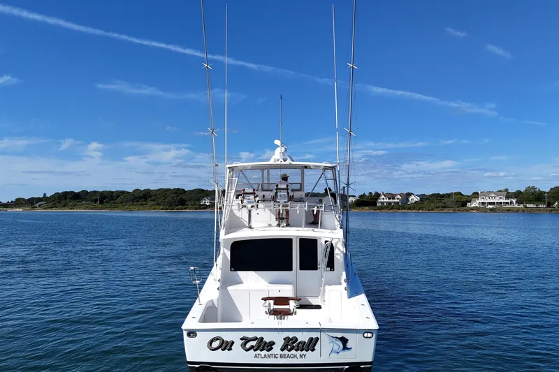 On The Ball Yacht Photos Pics 2006 Viking 56 Convertible boat on water, clear sky, coastal homes in background.