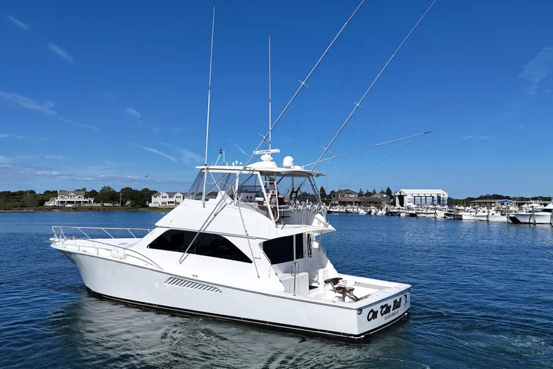 On The Ball Yacht Photos Pics 2006 Viking 56 Convertible yacht cruising in a scenic marina under a clear blue sky.
