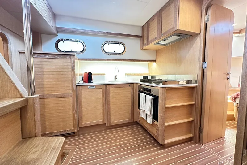  Yacht Photos Pics Elegant kitchen interior of 2026 Sasga Yachts Menorquin 48FB with wood finish and modern appliances.