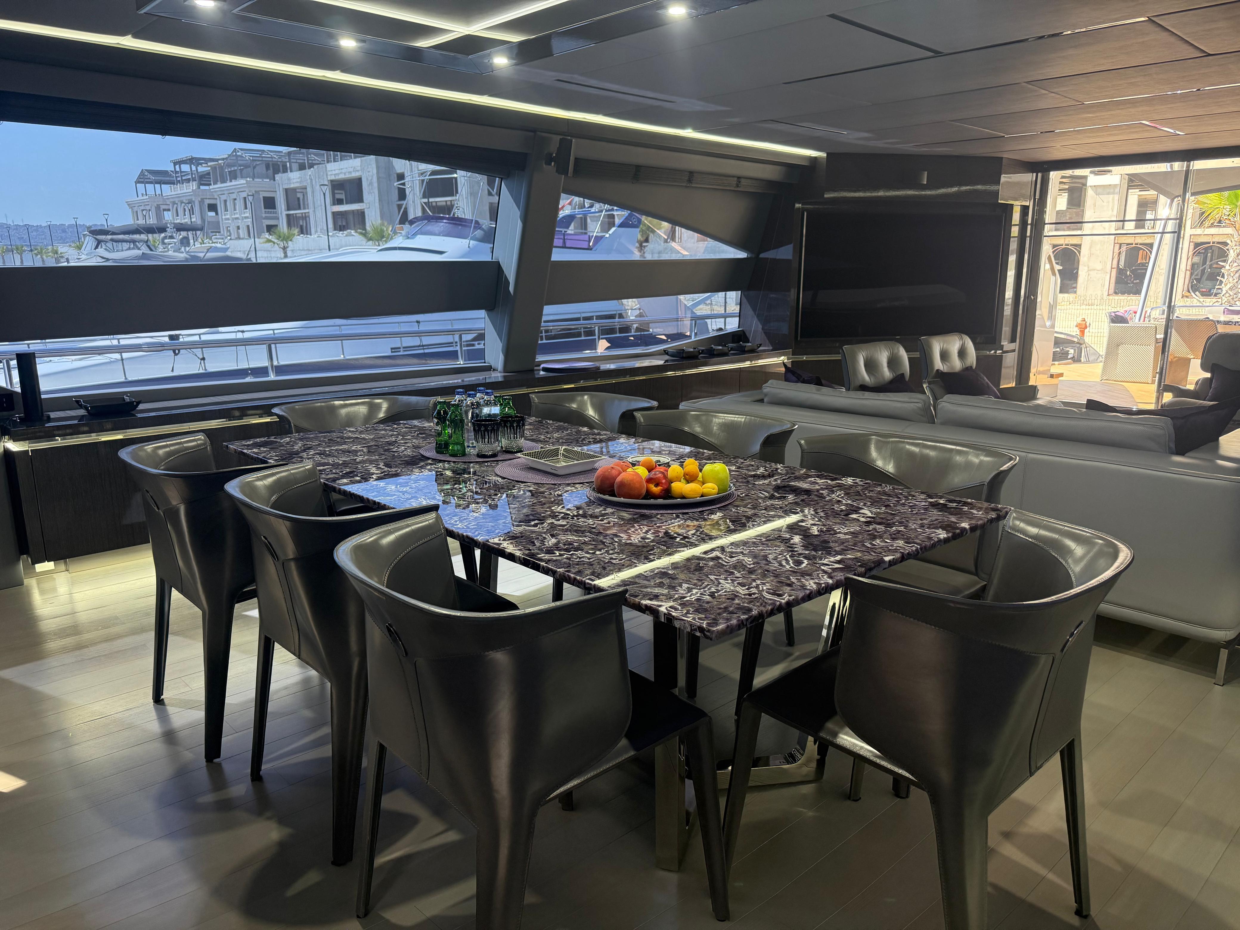 Luxurious yacht interior with marble dining table, leather chairs, and waterfront view. AB 100, 2017.