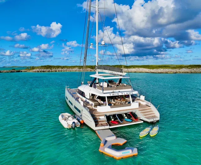 Twin Flame Yacht Photos Pics Luxurious 2020 Lagoon Seventy 7 yacht anchored in turquoise waters, featuring water sports equipment.