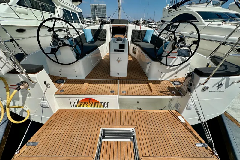 Endless Summer Yacht Photos Pics 2024 Jeanneau Sun Odyssey 410 yacht with dual steering wheels and teak deck, docked in marina.