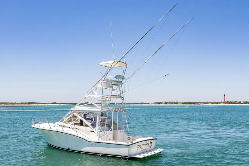 Patriot Yacht Photos Pics 2005 Carolina Classic 32 boat on clear blue water with distant lighthouse.