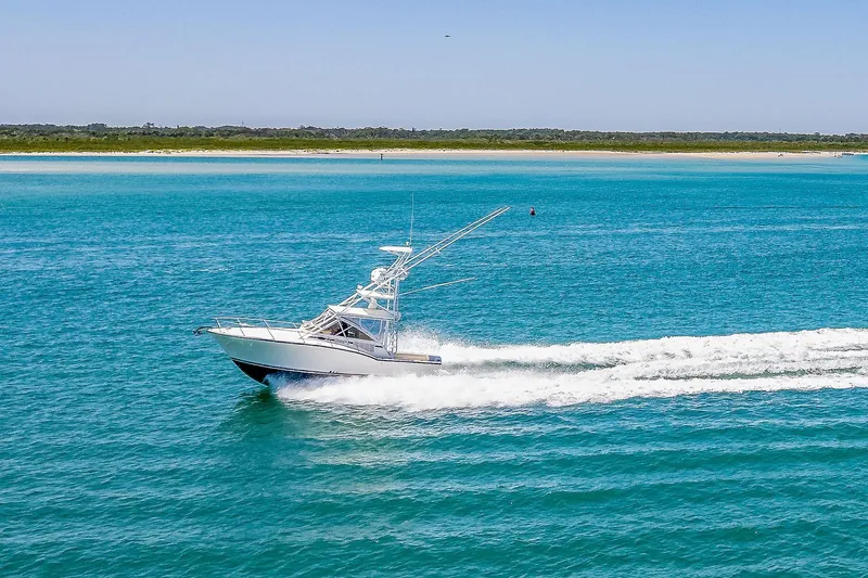Patriot Yacht Photos Pics 2005 Carolina Classic 32 boat cruising on clear blue water near a sandy shoreline.