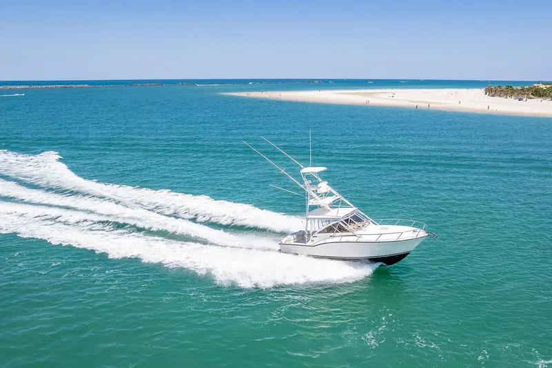 Patriot Yacht Photos Pics 2005 Carolina Classic 32 boat cruising on clear blue ocean near sandy beach.