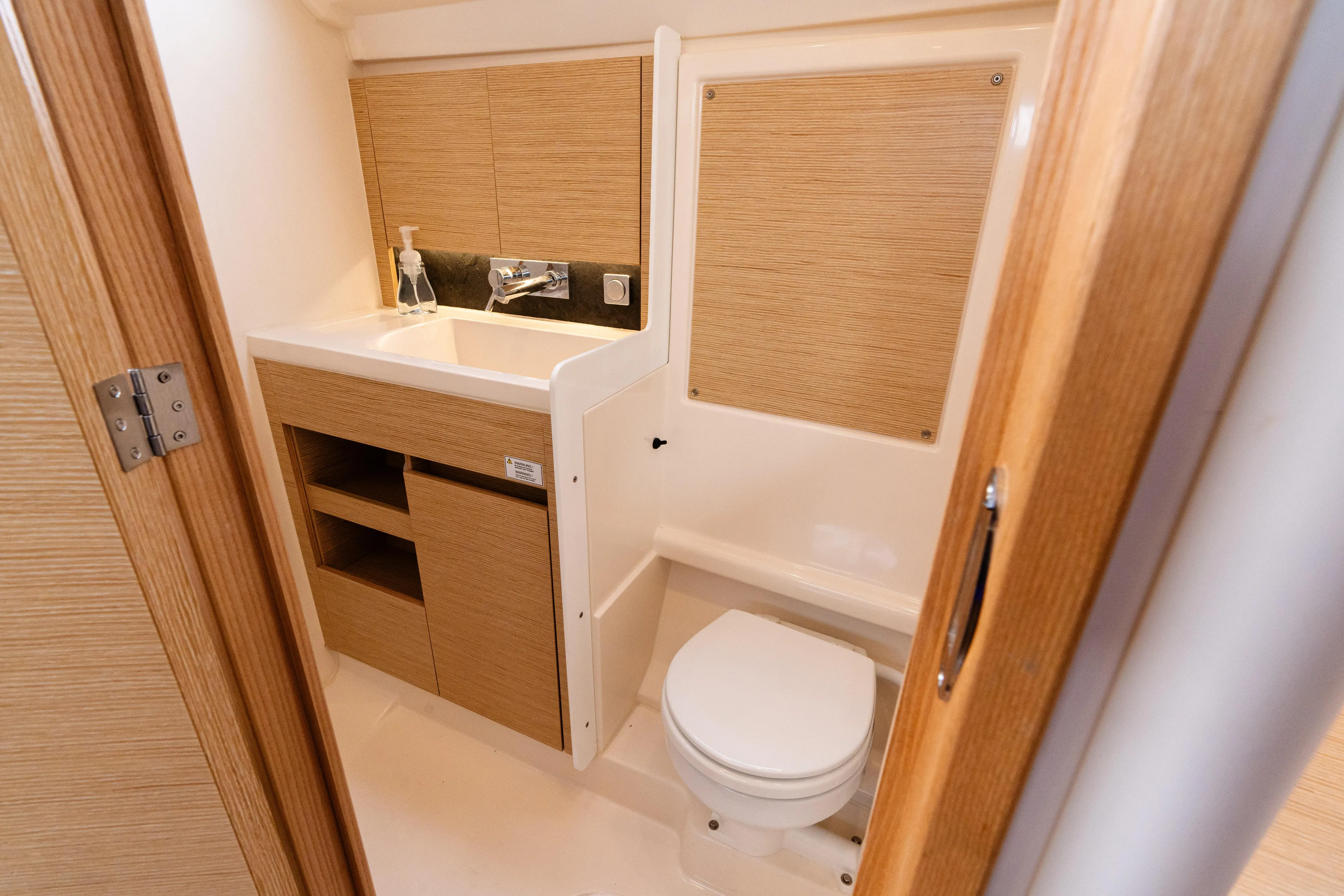 The Siren's Song Yacht Photos Pics Modern bathroom in 2023 Hanse 348 yacht with wooden cabinetry and compact design.