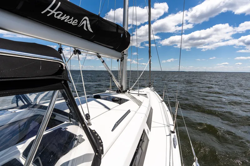 The Siren's Song Yacht Photos Pics 2023 Hanse 348 sailboat on open water under a blue sky with clouds.