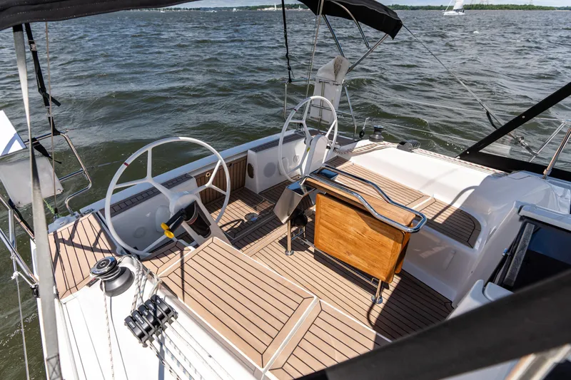 The Siren's Song Yacht Photos Pics 2023 Hanse 348 sailboat cockpit with dual steering wheels and wooden deck on open water.