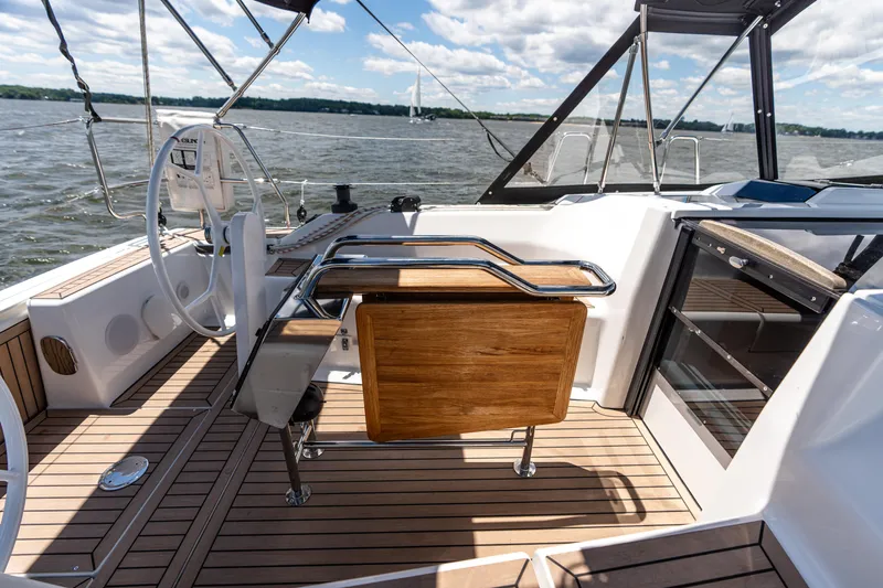 The Siren's Song Yacht Photos Pics 2023 Hanse 348 yacht cockpit with wooden flooring and steering wheel on open water.