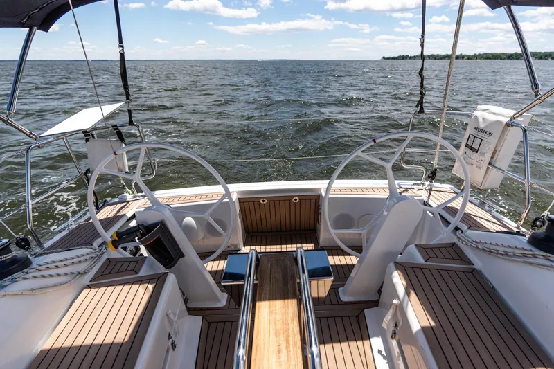 The Siren's Song Yacht Photos Pics 2023 Hanse 348 sailboat cockpit with dual steering wheels, wooden deck, and ocean view.