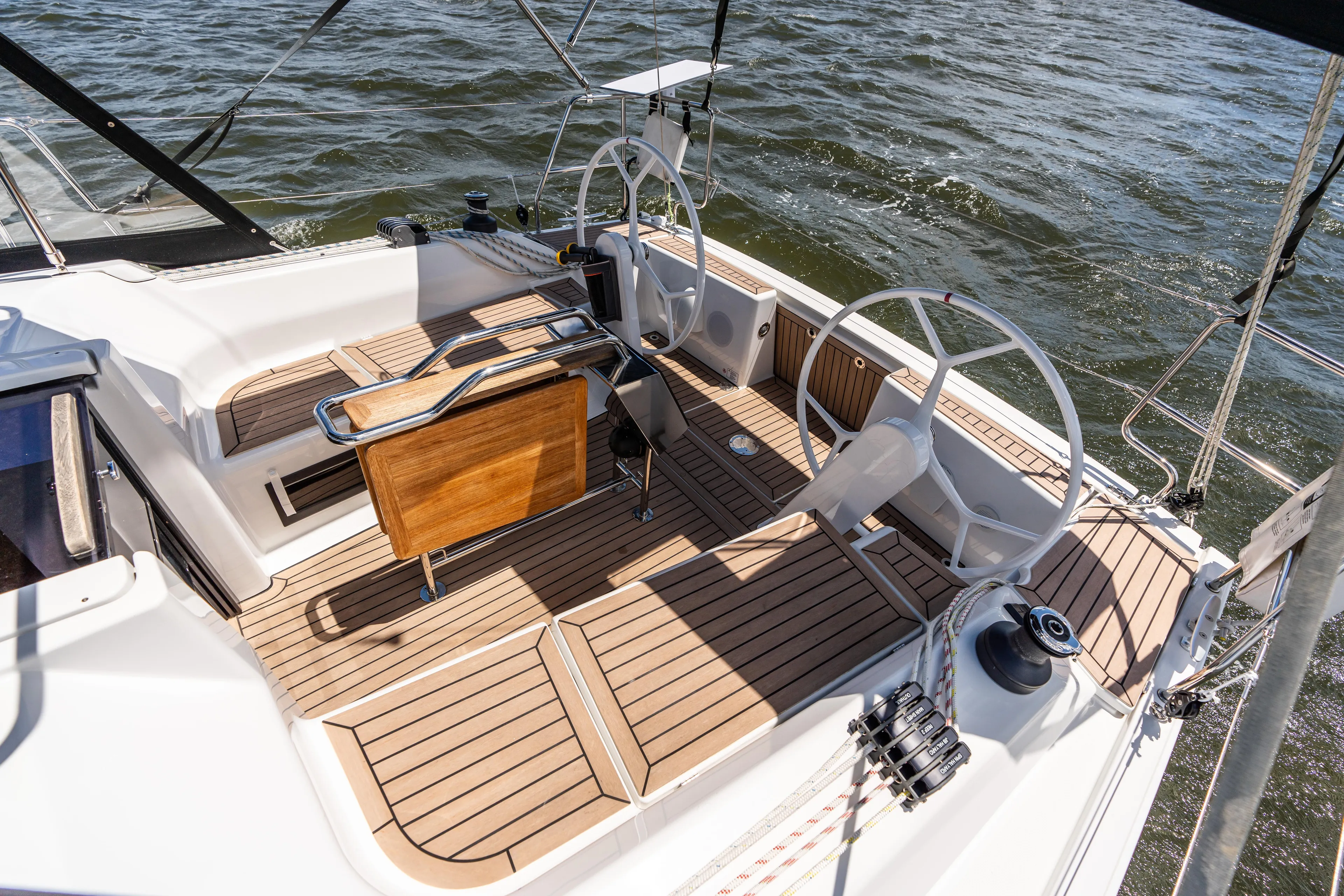 The Siren's Song Yacht Photos Pics 2023 Hanse 348 sailboat cockpit with dual steering wheels and teak flooring on the water.