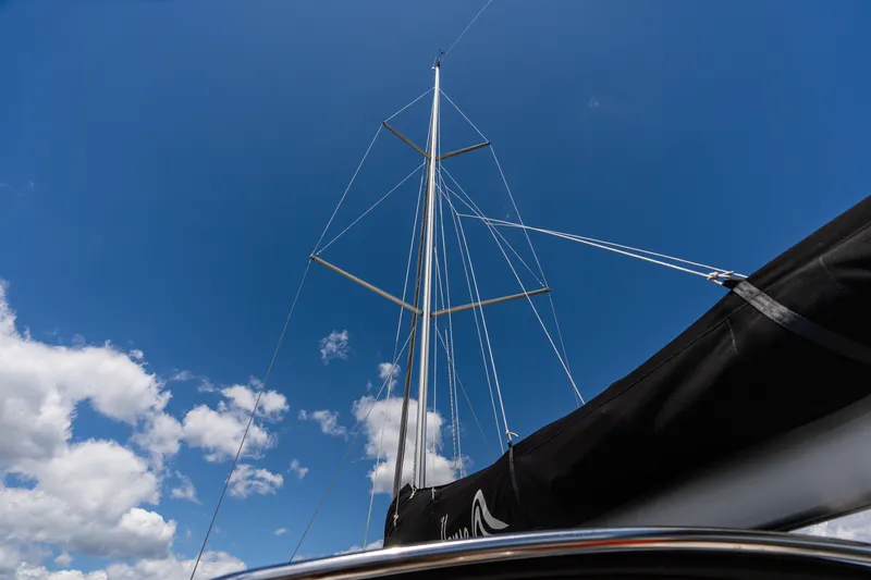 The Siren's Song Yacht Photos Pics Mast of 2023 Hanse 348 sailboat against a clear blue sky with clouds.