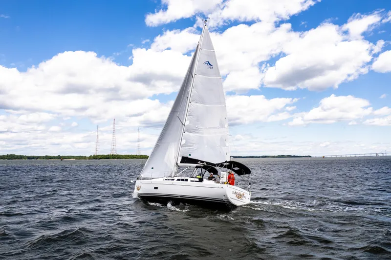 The Siren's Song Yacht Photos Pics 2023 Hanse 348 sailboat navigating on a sunny day with blue skies and clouds.