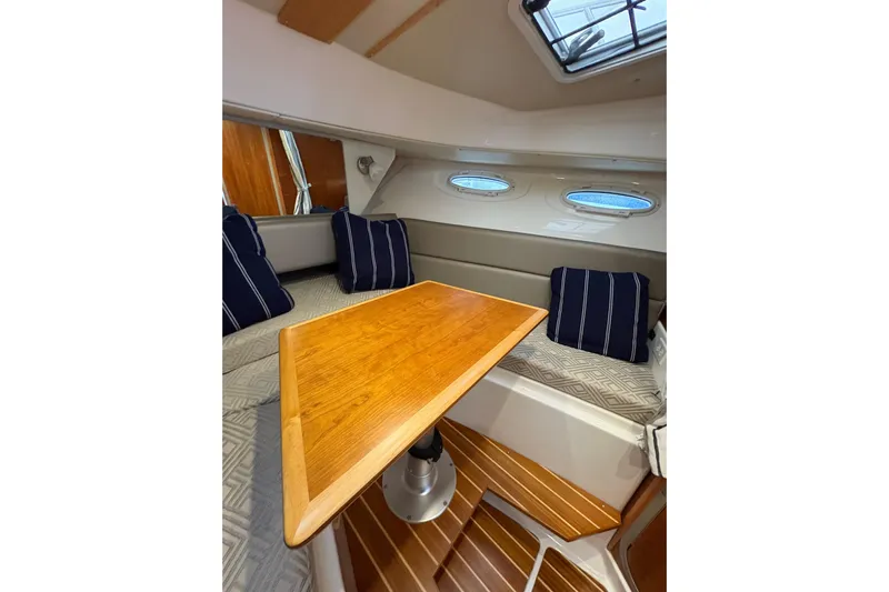 Andiamo Yacht Photos Pics Interior of 2020 Cutwater C-28 boat with wooden table and striped cushions.