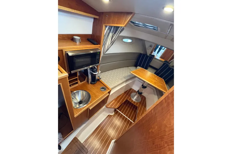 Andiamo Yacht Photos Pics 2020 Cutwater C-28 interior with kitchenette, seating area, and wooden finishes.