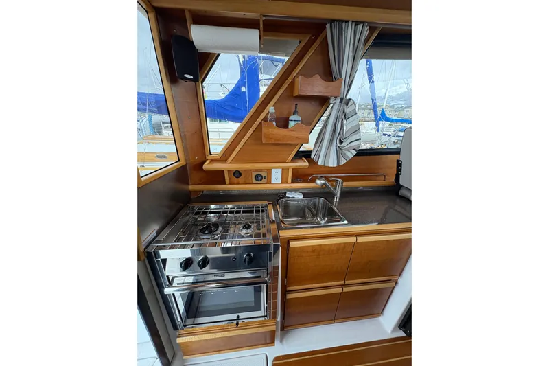 Andiamo Yacht Photos Pics 2020 Cutwater C-28 boat kitchen with stove, sink, and wooden cabinetry.