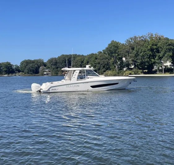 Sea Lion Yacht Photos Pics 2019 Boston Whaler 420 Outrage boat on calm water, surrounded by trees.