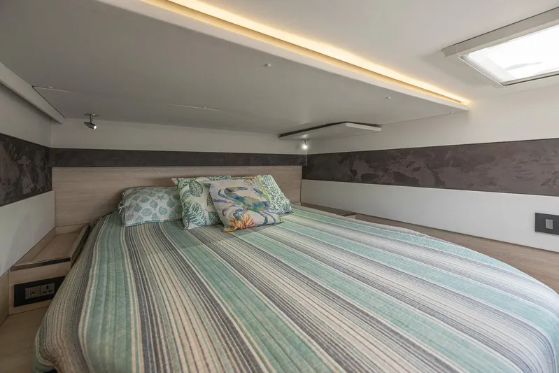 One Love Yacht Photos Pics Cozy bedroom in a 2019 Leopard 50 yacht with striped bedding and decorative pillows.