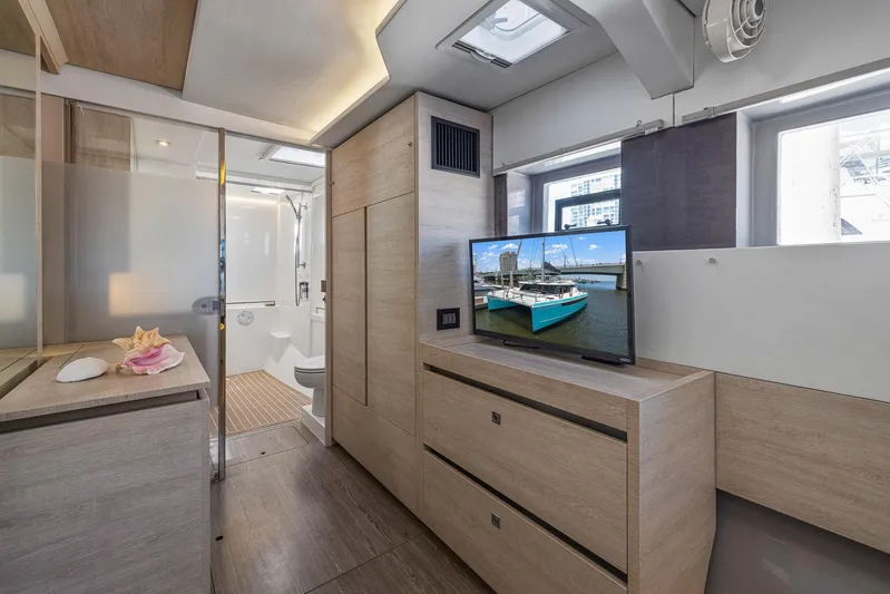 One Love Yacht Photos Pics Modern interior of 2019 Leopard 50 yacht with TV, bathroom, and wooden cabinetry.