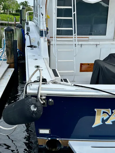 Farbrengen Yacht Photos Pics 1982 Bertram 54 Convertible yacht docked, featuring a ladder and fender.