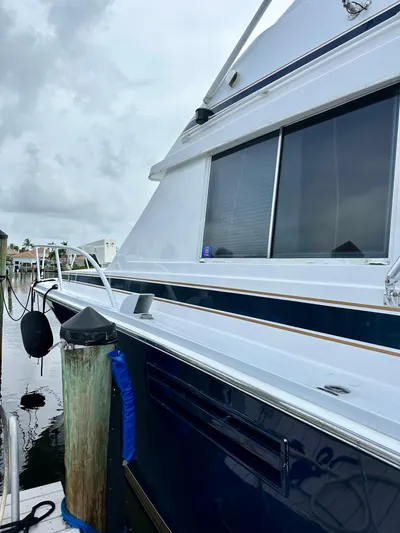 Farbrengen Yacht Photos Pics 1982 Bertram 54 Convertible yacht docked, showcasing sleek design and windows.
