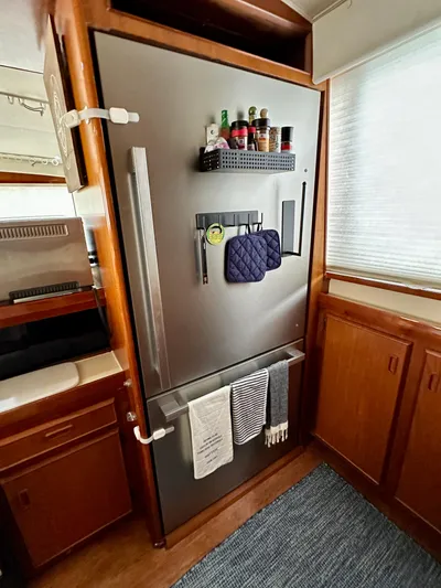 Farbrengen Yacht Photos Pics Modern kitchen area in a 1982 Bertram 54 Convertible yacht, featuring a stainless steel refrigerator.