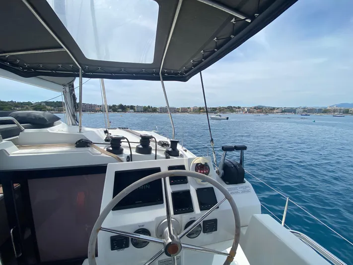 Enotan Yacht Photos Pics Cockpit view of 2020 Fountaine Pajot Saona 47 catamaran sailing near coastal town.