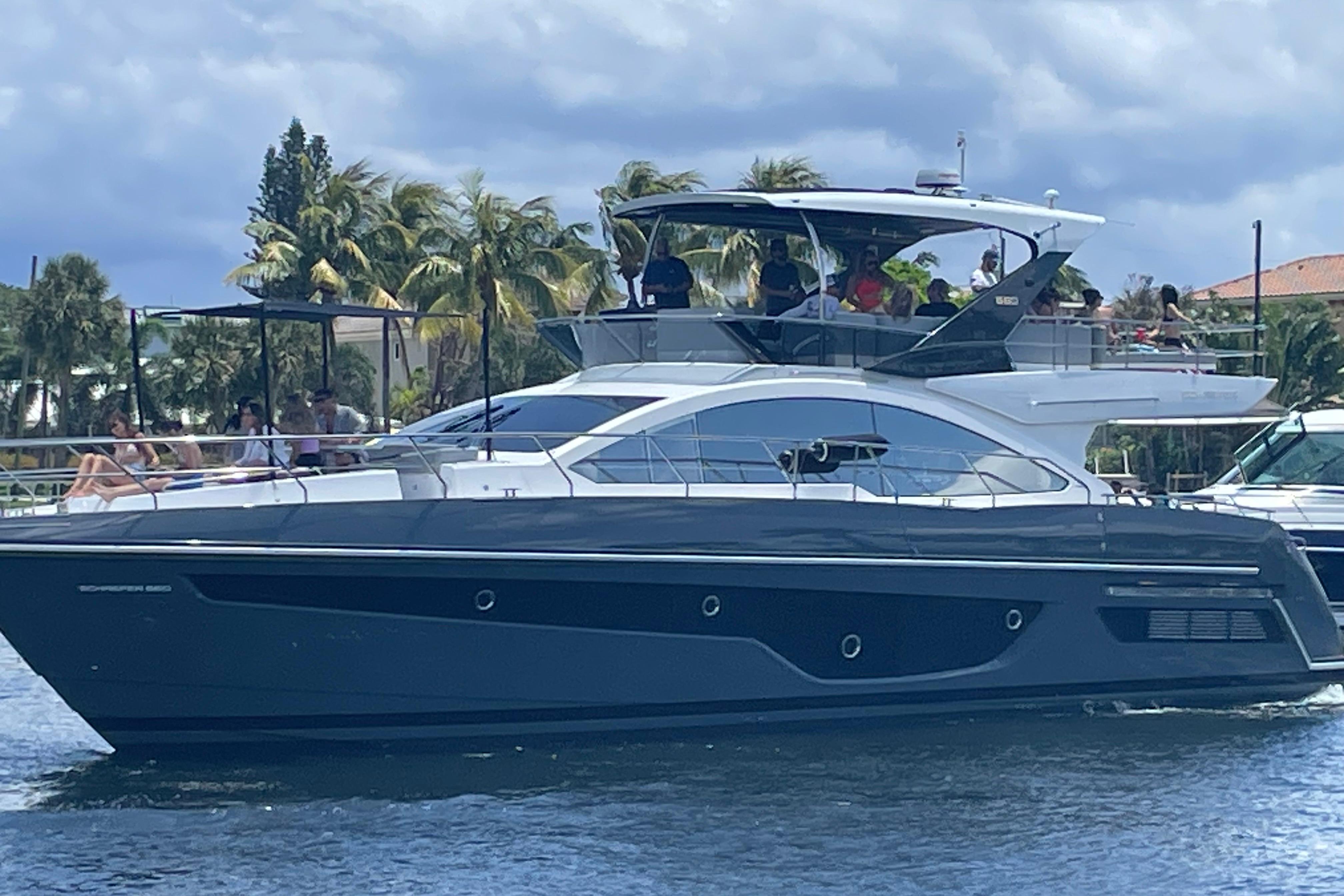 Luxury Schaefer 660 yacht cruising on water, 2023 model, with passengers enjoying the view.