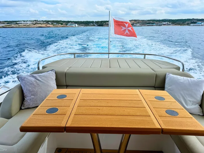 The Office Yacht Photos Pics Sunseeker Manhattan 55 yacht deck with table, cushions, and Maltese flag, 2015 model.