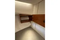 Interior of 2023 Nimbus 305 Coupe showing open wooden cabinet with lighting.