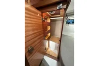 Interior view of 2023 Nimbus 305 Coupe wooden cabinet with open door.