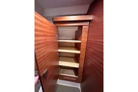 Wooden cabinet with open door and shelves inside a 2023 Nimbus 305 Coupe.