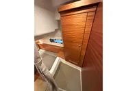 Interior cabin of 2023 Nimbus 305 Coupe with wooden cabinetry and small window.