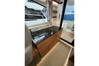 Interior of 2023 Nimbus 305 Coupe, featuring sleek kitchen with modern cabinetry and black countertop.