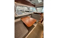 Interior of 2023 Nimbus 305 Coupe with wooden table and cushioned seating.