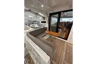 2023 Nimbus 305 Coupe interior with seating and wooden table in a boat showroom.
