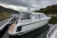 2023 Nimbus 305 Coupe docked on a calm waterway under cloudy skies.