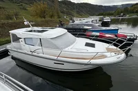 2023 Nimbus 305 Coupe docked on a calm river with scenic background.