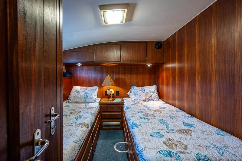 Miss Print IV Yacht Photos Pics 1987 Hatteras 52 Convertible twin bed cabin with wooden paneling and nautical-themed bedding.