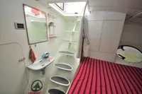 Interior of 2008 Trimaran POLYNESIA 42 with stairs, sink, and striped bed.