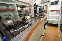 Interior of 2008 Trimaran POLYNESIA 42, featuring a compact kitchen with stove and sink.
