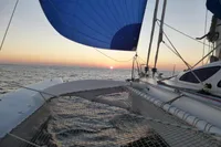Trimaran POLYNESIA 42 sailing at sunset, 2008 model, with blue sail and ocean view.