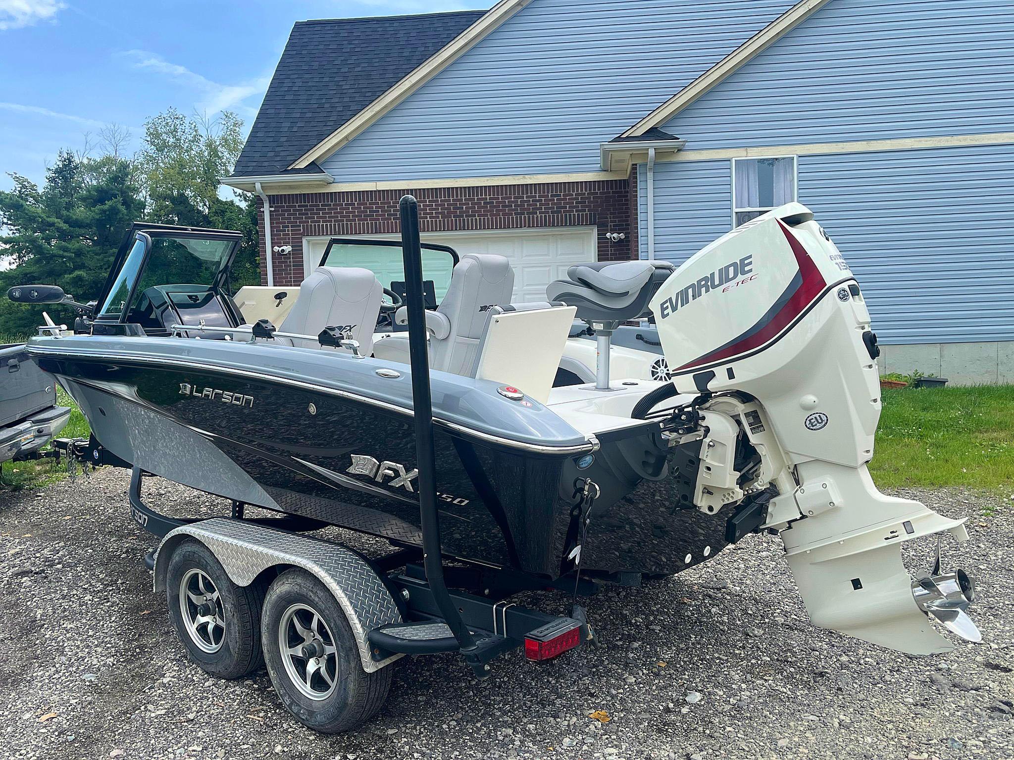 2018 Larson 1850 FX DC boat with Evinrude motor on trailer, parked in driveway.