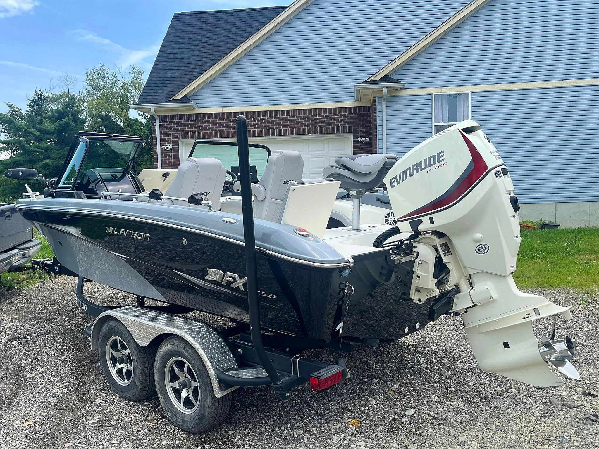 2018 Larson 1850 FX DC boat with Evinrude motor on trailer, parked in driveway.