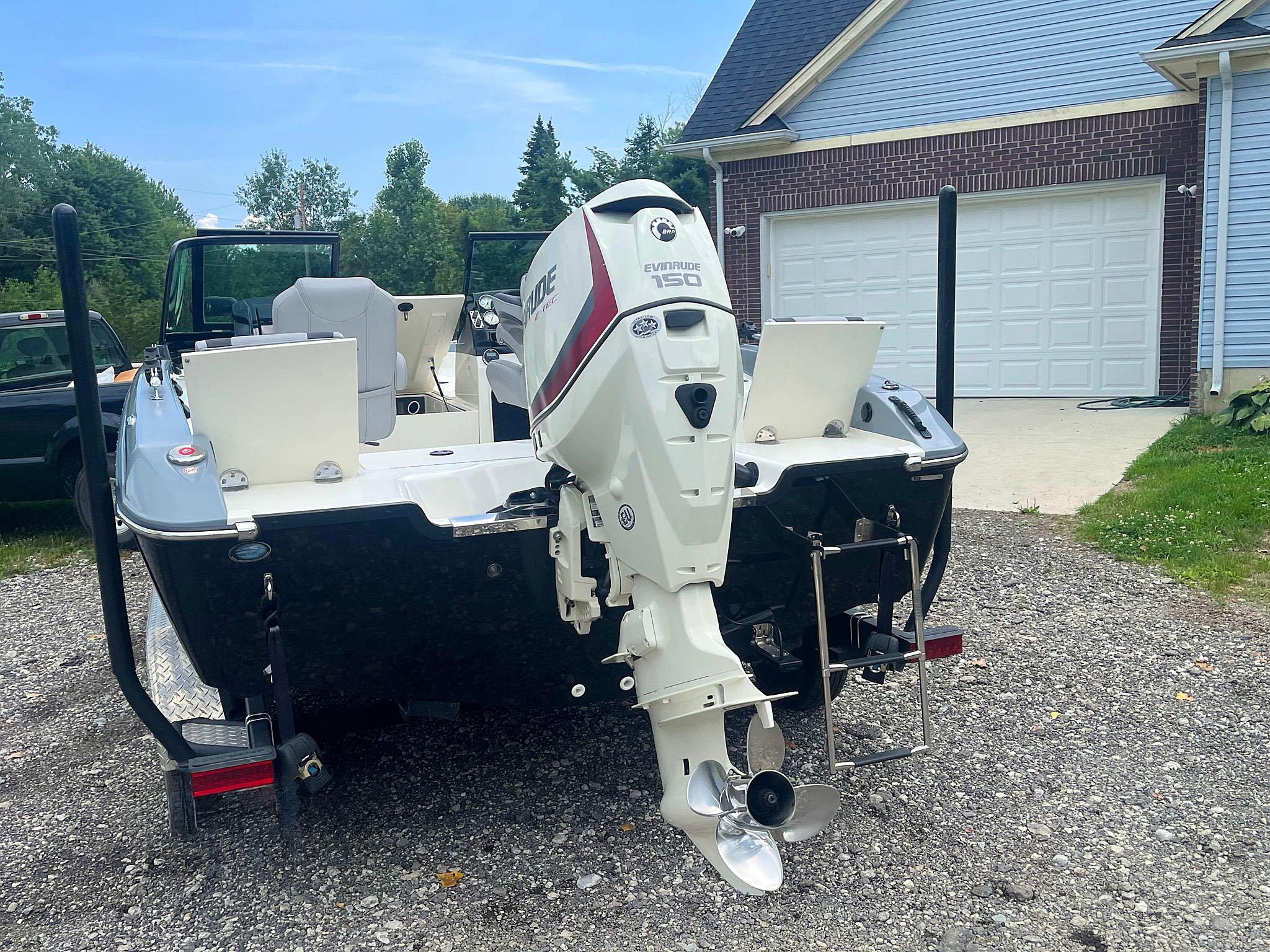 2018 Larson 1850 FX DC boat with Evinrude motor, parked on gravel driveway.
