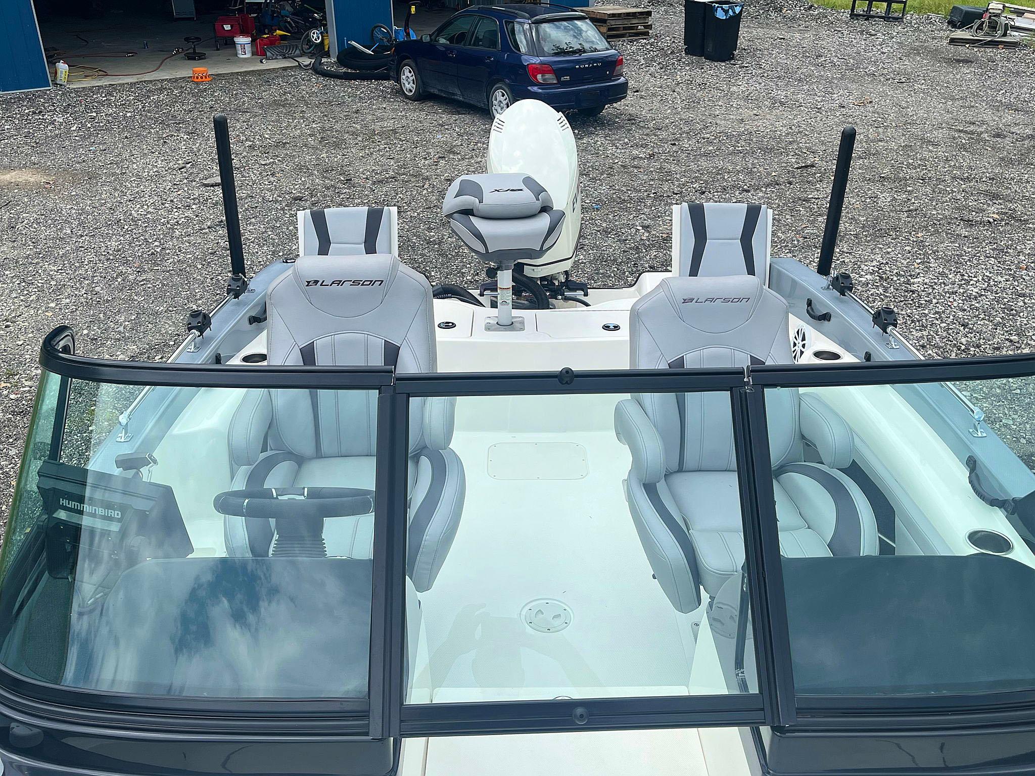 2018 Larson 1850 FX DC boat with dual consoles and seating, parked on gravel.